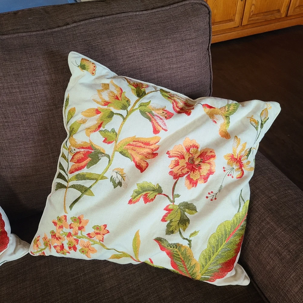 2 pillows with embroidered flowers and hummingbirds